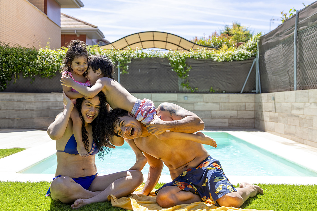 Happy family playing by the pool, parents and children enjoying